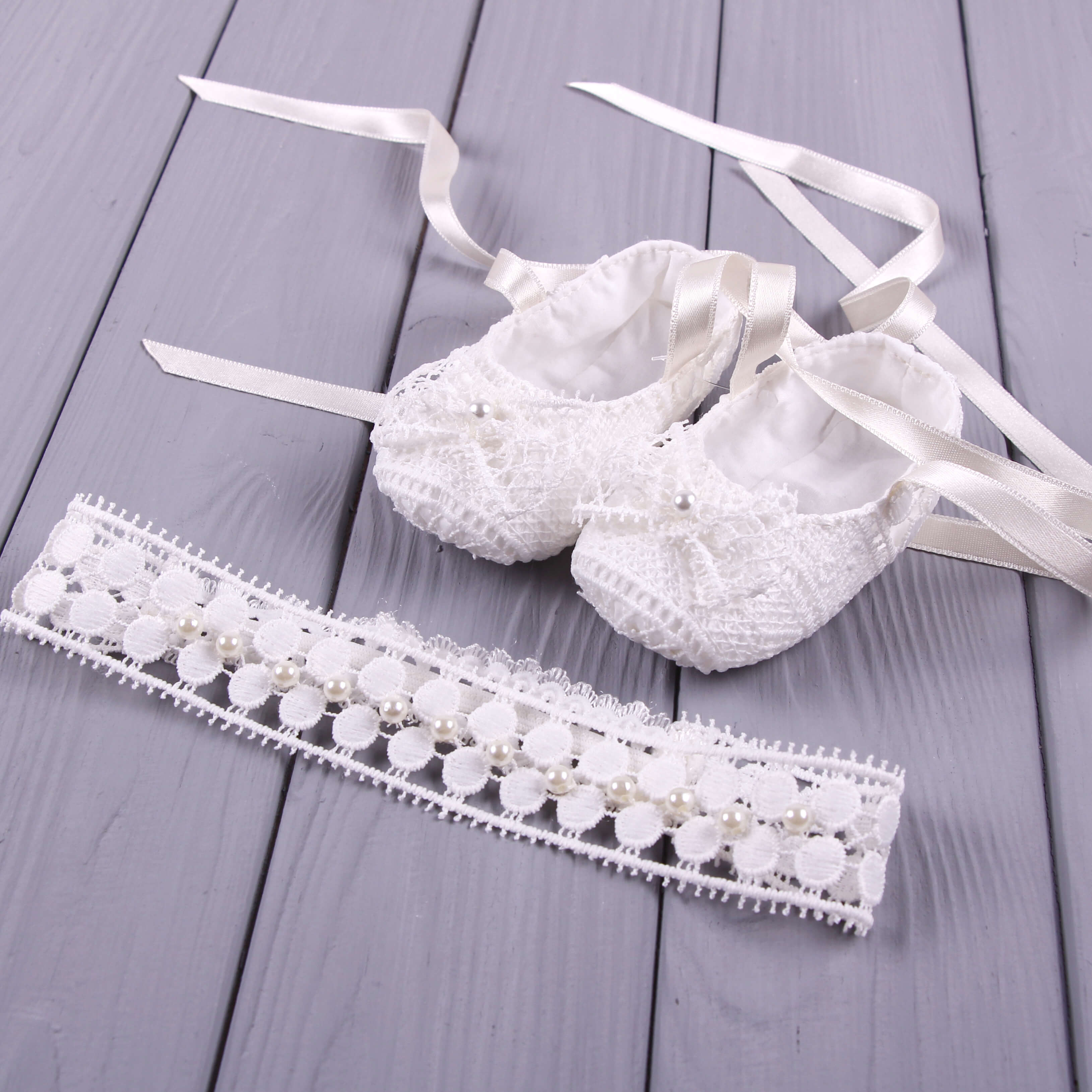 White lace garter and Baptism Booties on a wooden surface