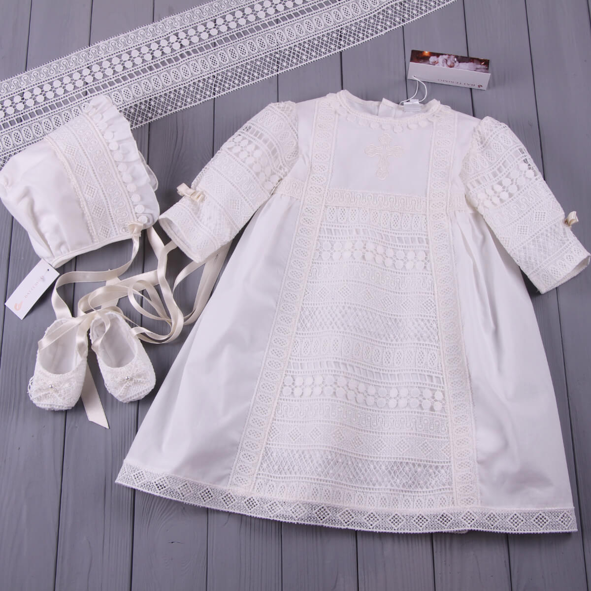 White baby dress with matching bonnet and Baptism Booties on a wooden surface