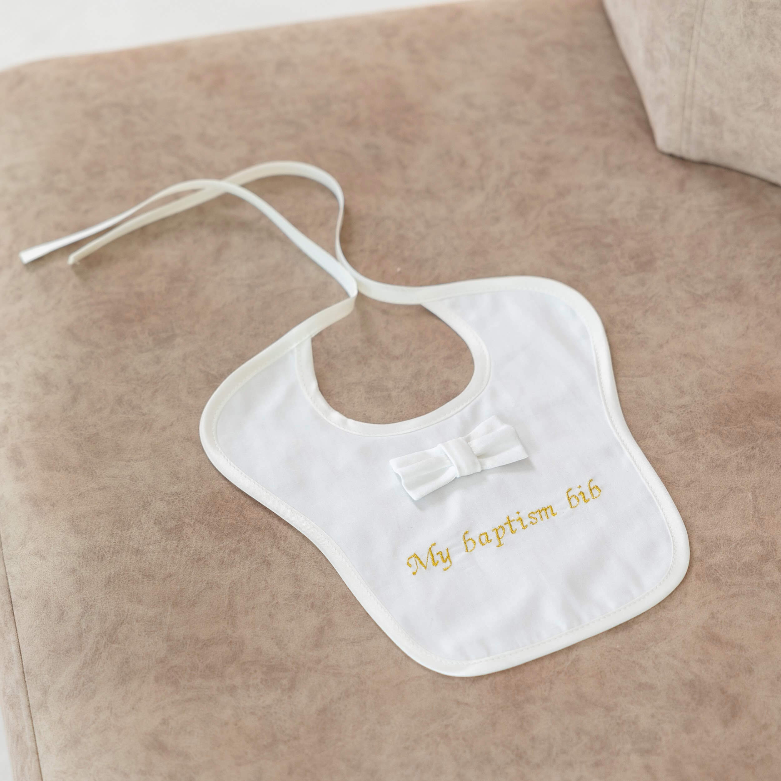 Baptism Bib  with 'My baptism bib' text and bow on a beige surface