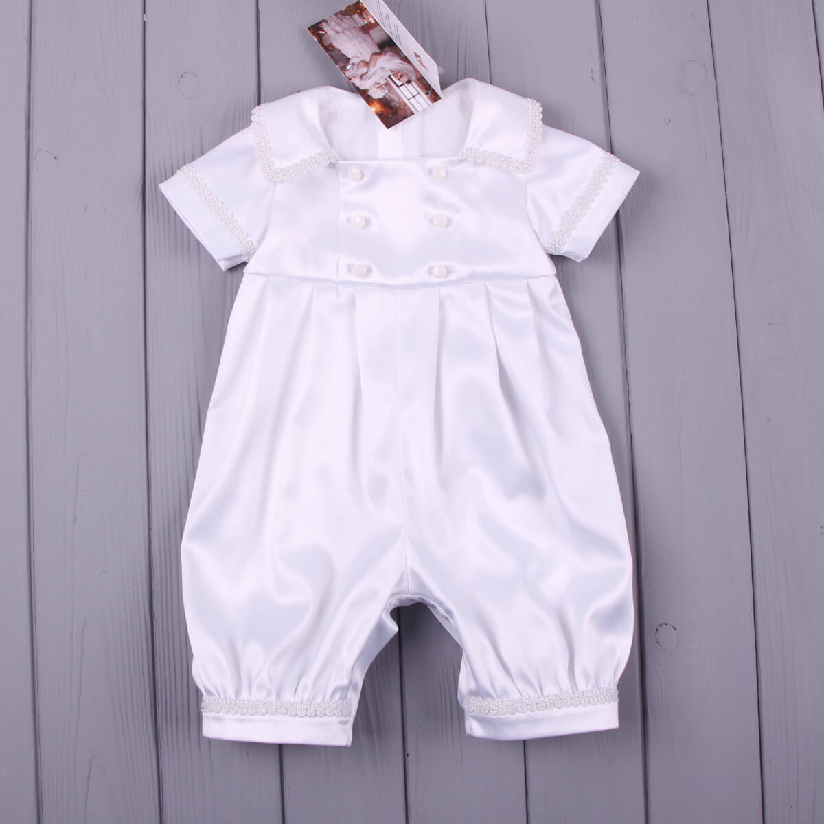 Boy Christening Outfitr with ruffled collar on a wooden surface