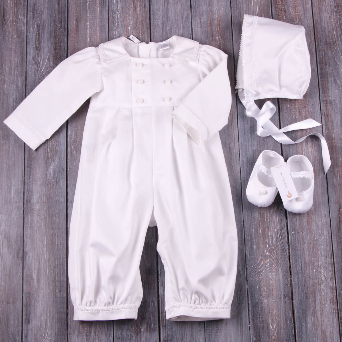 Boy Christening Outfit with bonnet and shoes on a wooden surface