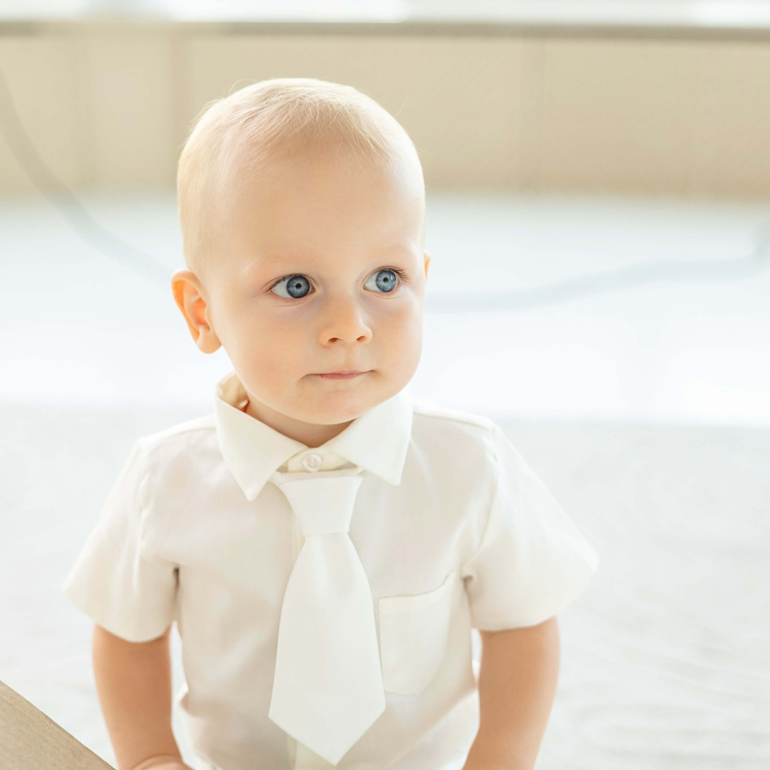 Baby wearing a wBaby Boy Baptism Suit with a bow tie against a neutral background