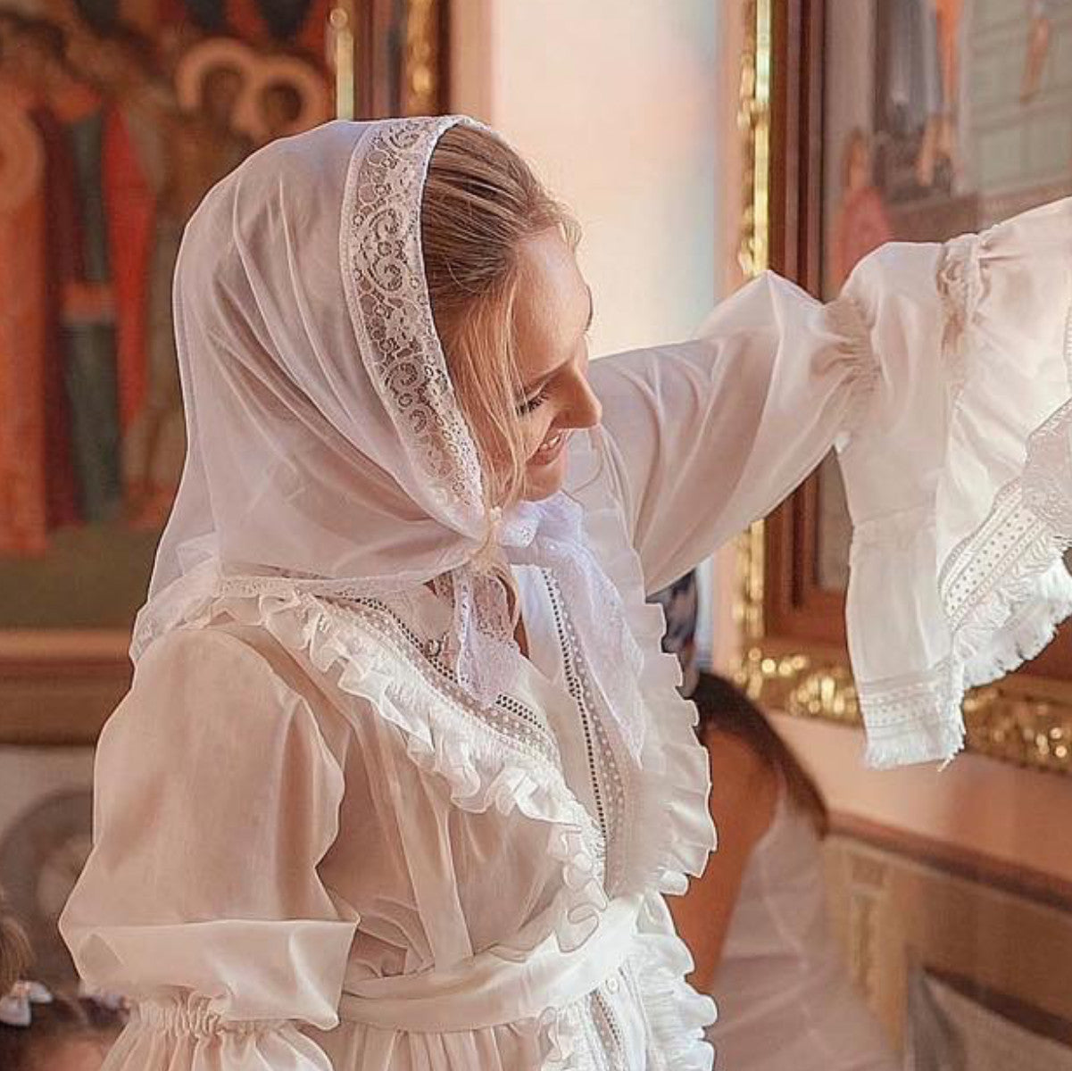 Woman in a white dress with Catholic Church Mantilla in an indoor setting