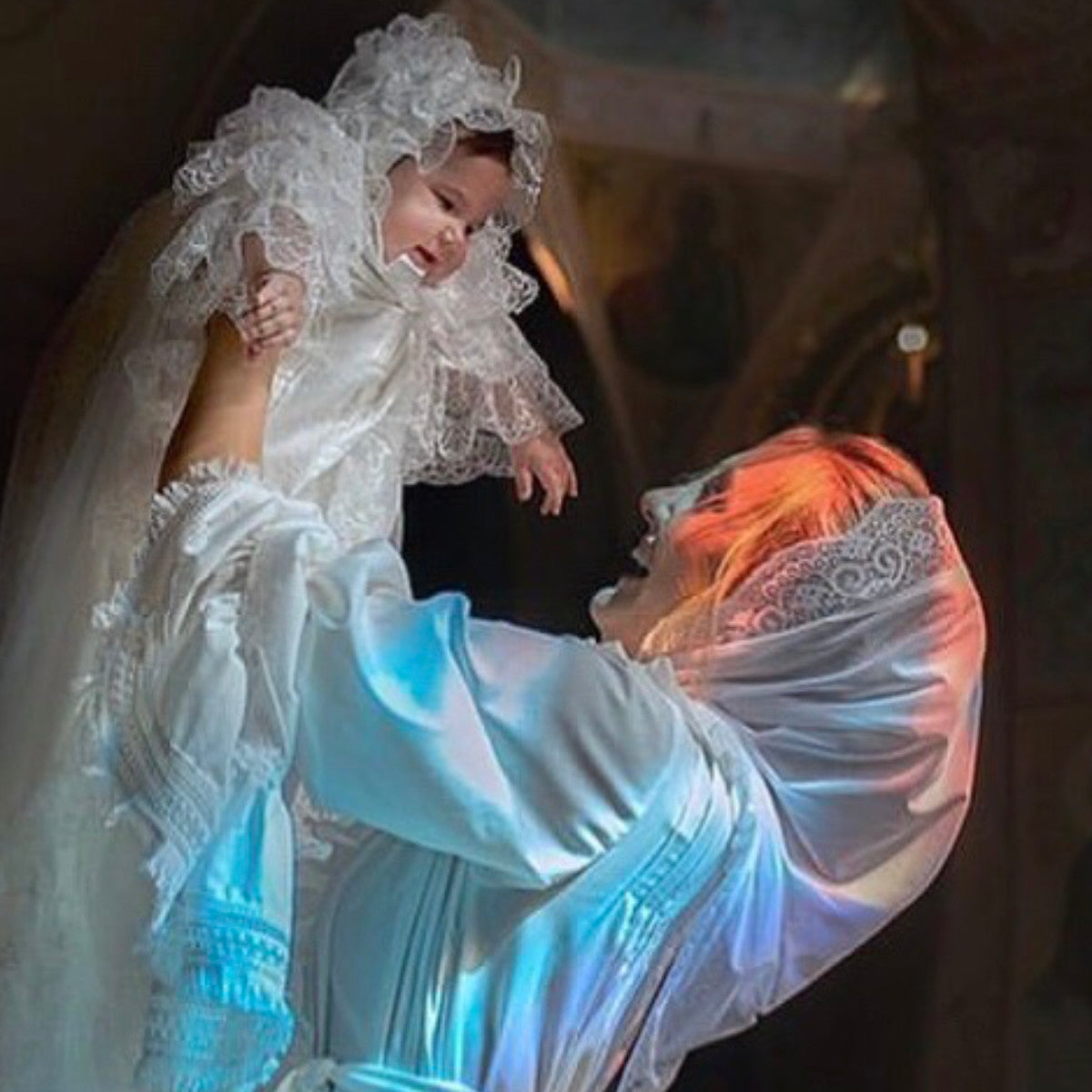 Person holding a baby wrapped in Catholic Church Mantilla h with a blurred background
