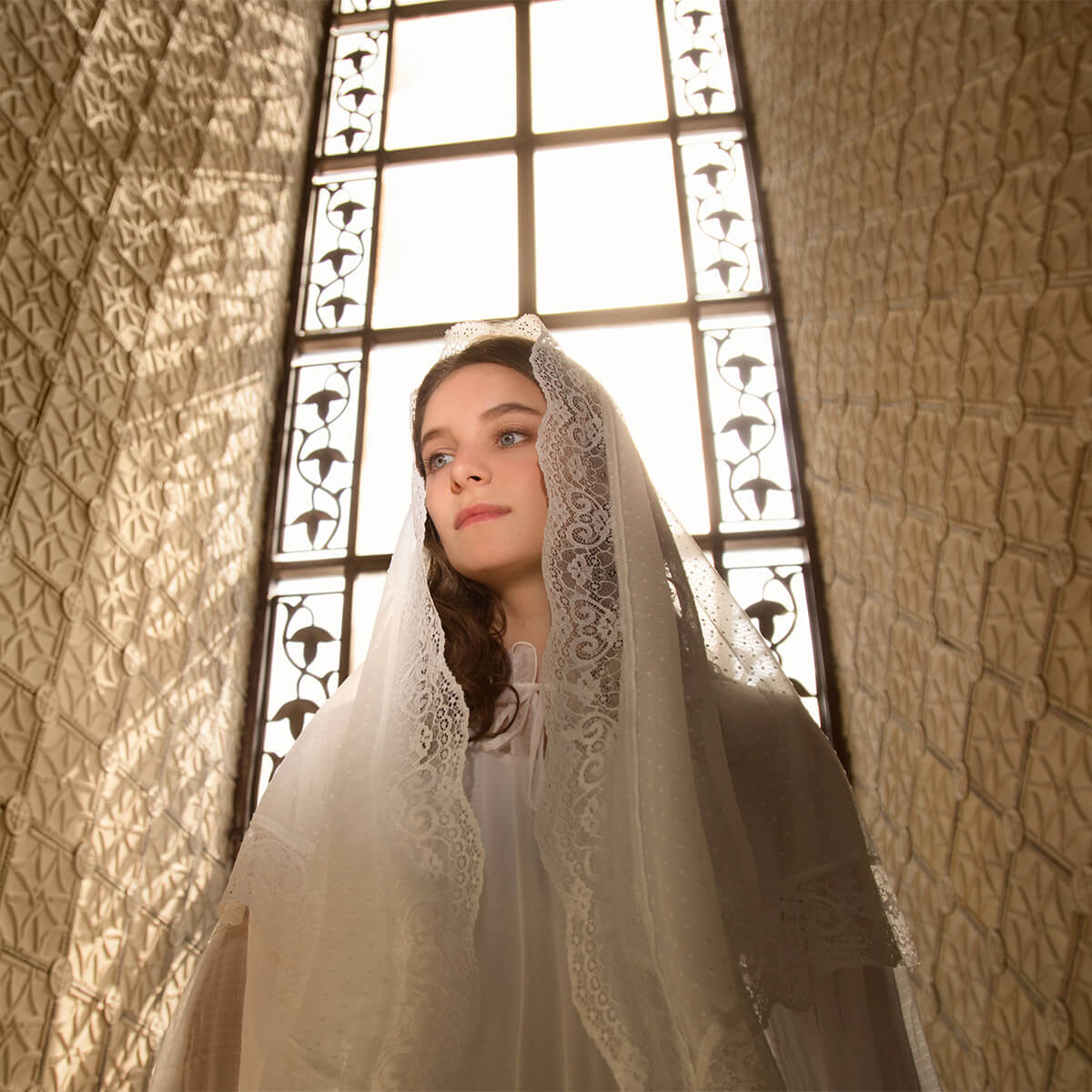 Woman wearing a Catholic Church Mantilla in front of a stained glass window