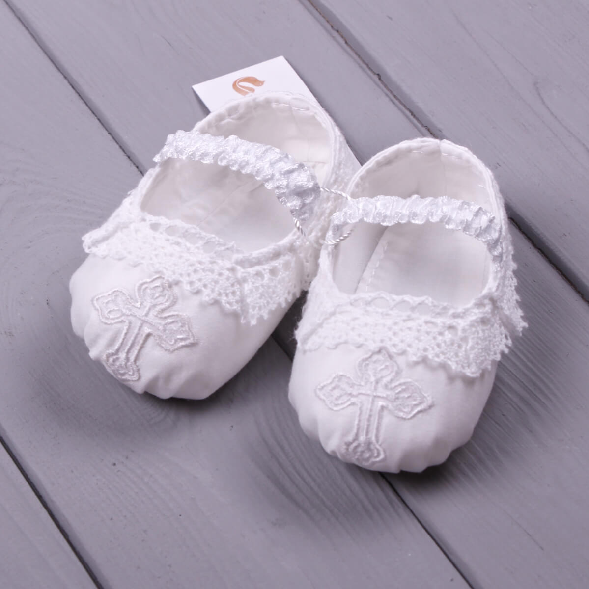 Christening Booties with lace details on a gray wooden surface