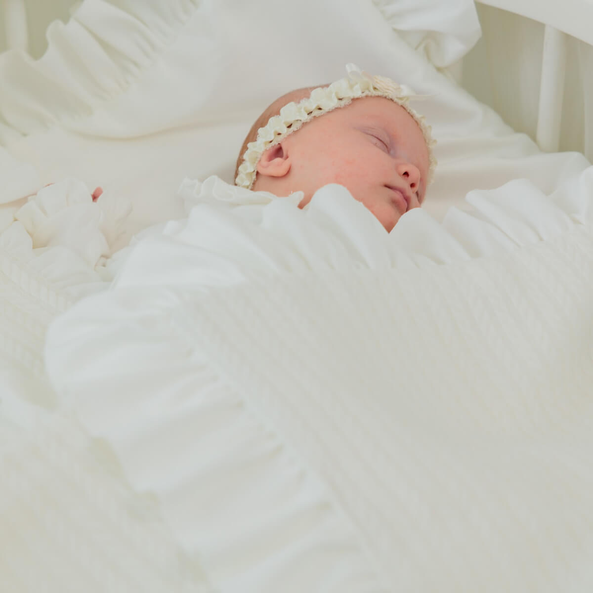 Newborn baby wrapped inNewborn Coming Home Blanket with lace headband