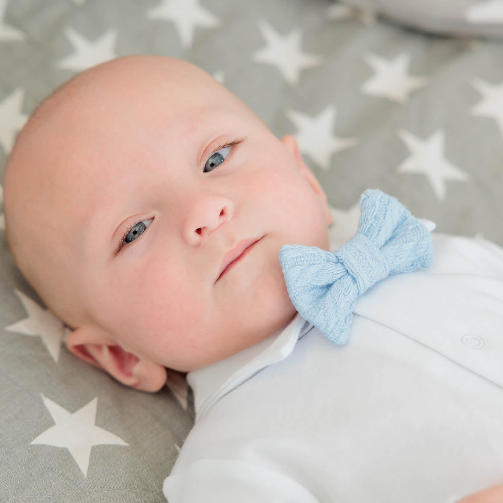 Baby in Newborn Coming Home Outfit with a blue bow lying on a star-patterned blanket