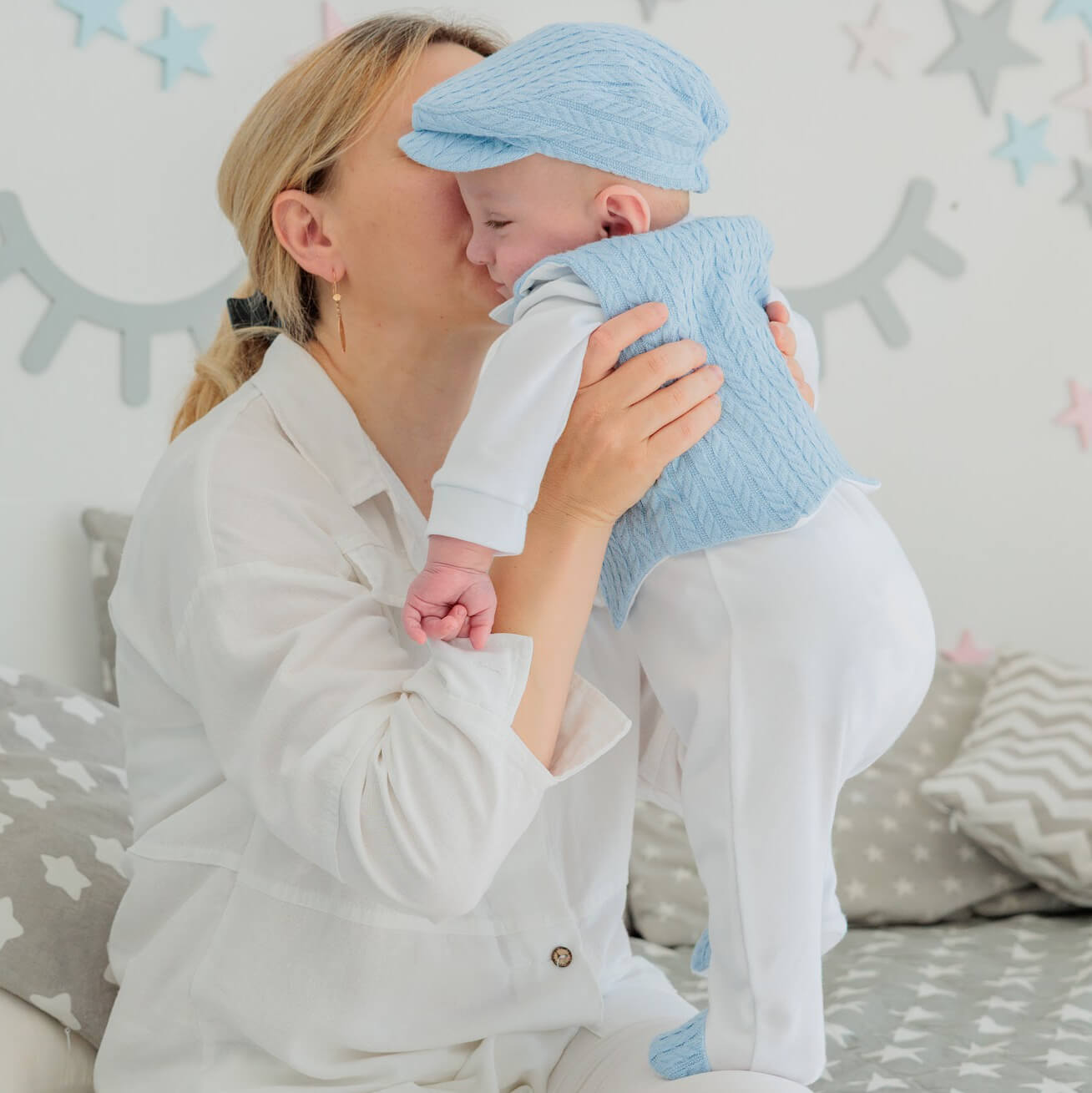 Woman holding a baby dressed in Newborn Coming Home Outfit against a neutral background