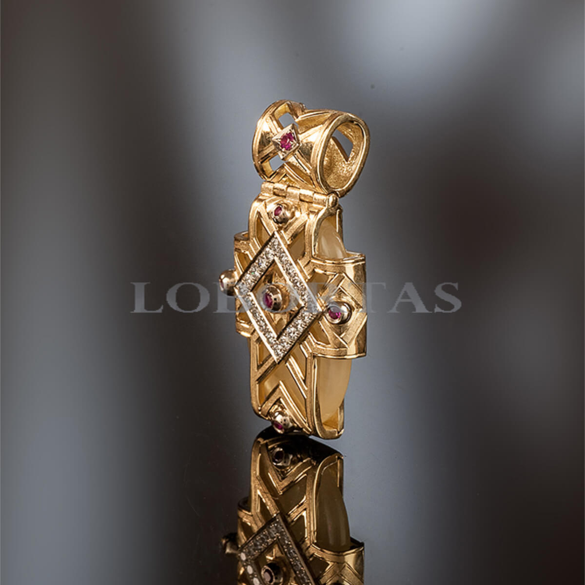 Gold pendant with gemstones on a reflective surface