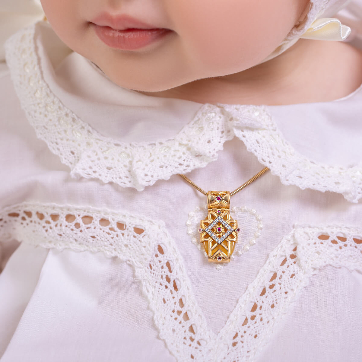 Close-up of a baby wearing a gold necklace with a diamond pendant.