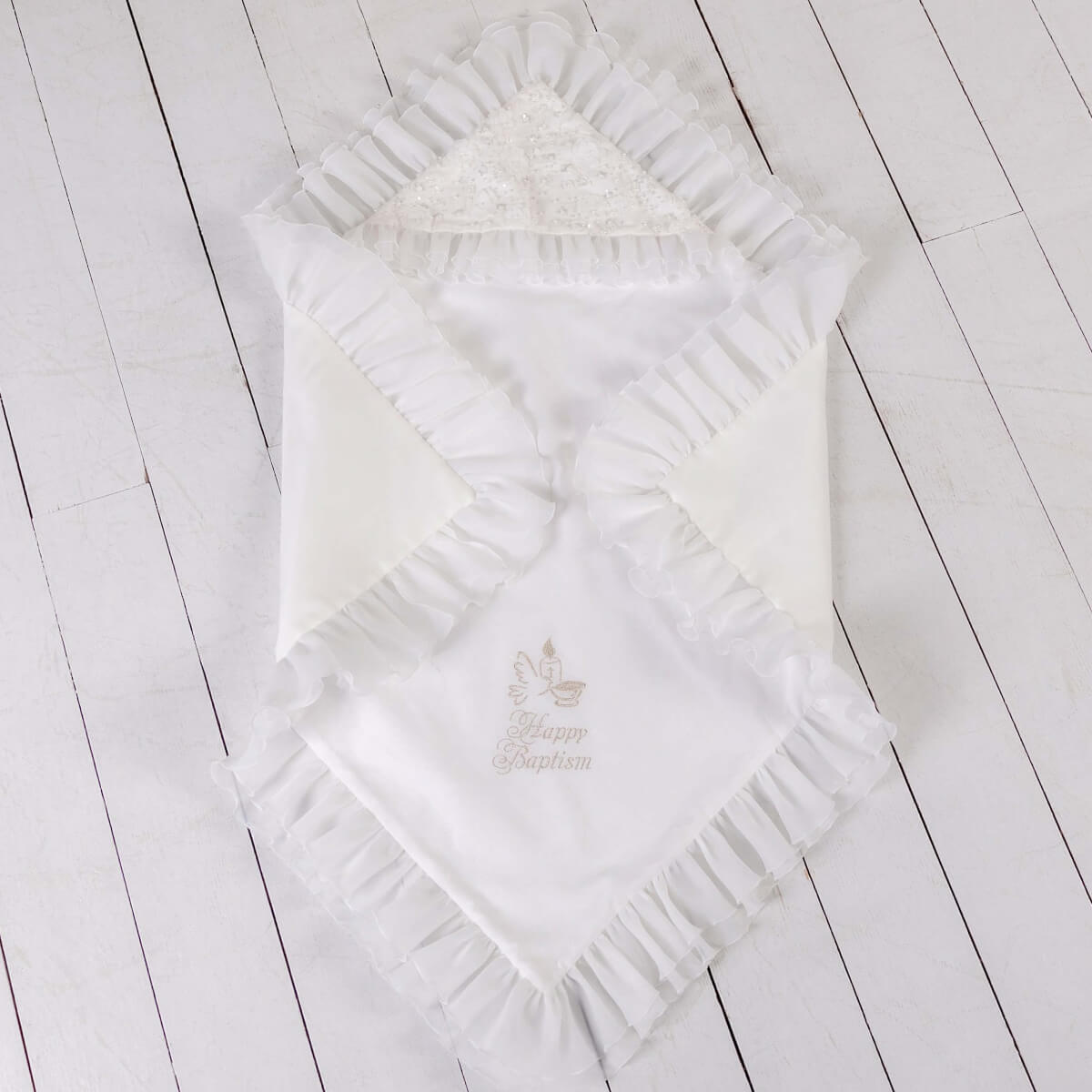 White baby blanket with ruffles on a light wooden floor