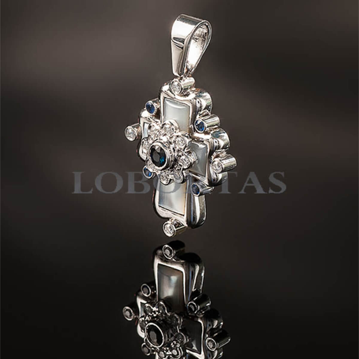 Silver pendant with gemstones on a reflective surface, brand 'LOBE' visible