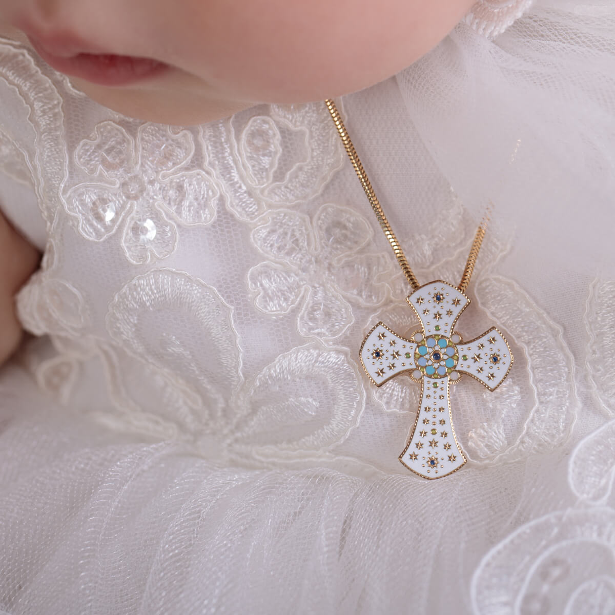 Close-up of a child wearing a gold necklace with a cross pendant.