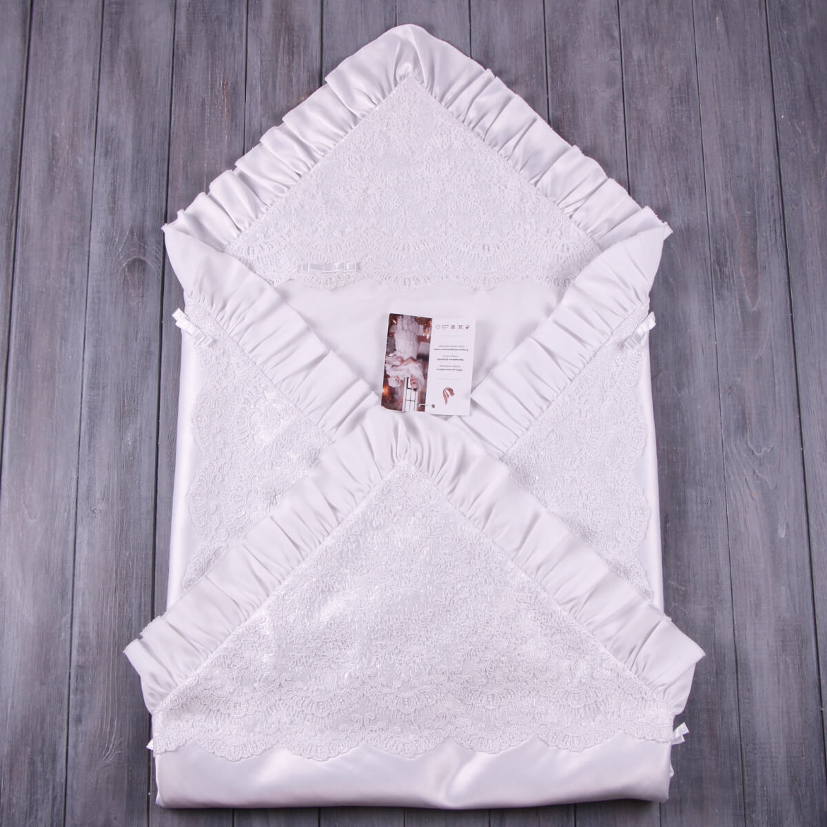 White christening blanket with ruffled edges on a wooden surface