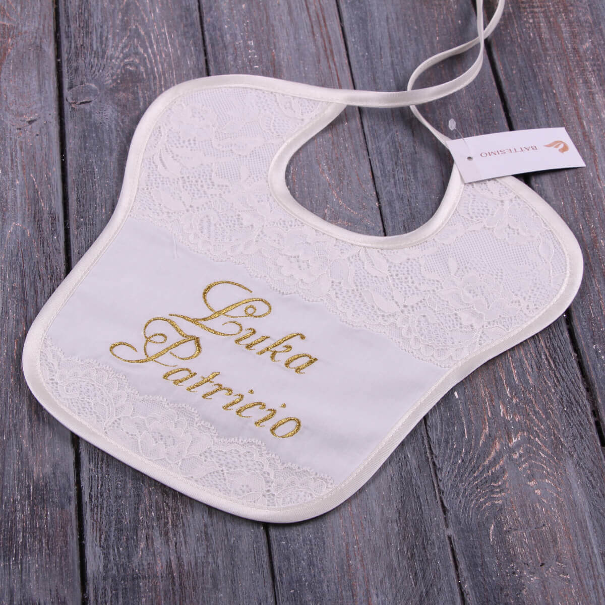 Baptism Bib with gold text on a wooden surface
