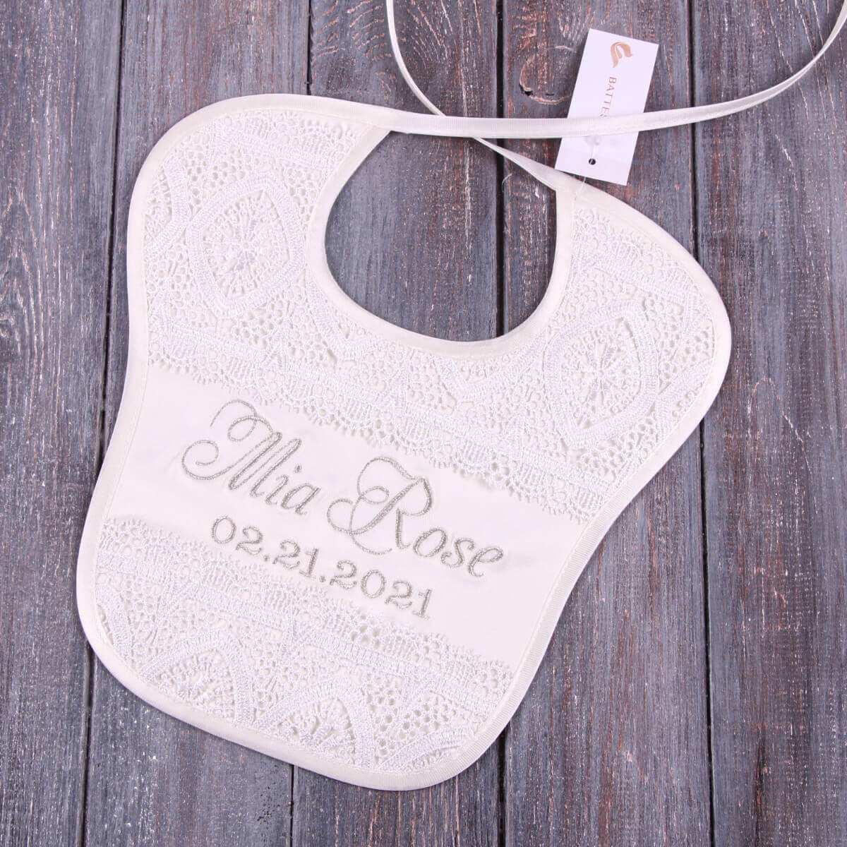 Baptism Bib with engraved text on a wooden surface