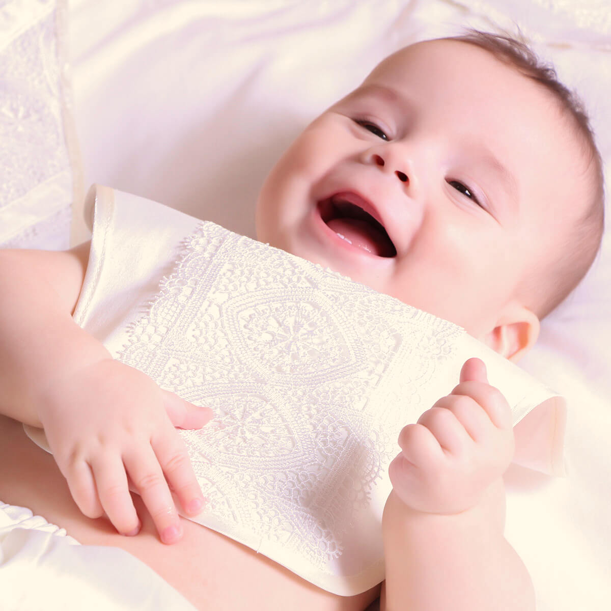 Baby holding a Baptism Bib with a soft focus background