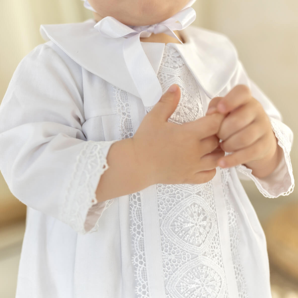 Close-up of a child wearing a white lace christening gown with a blurred background