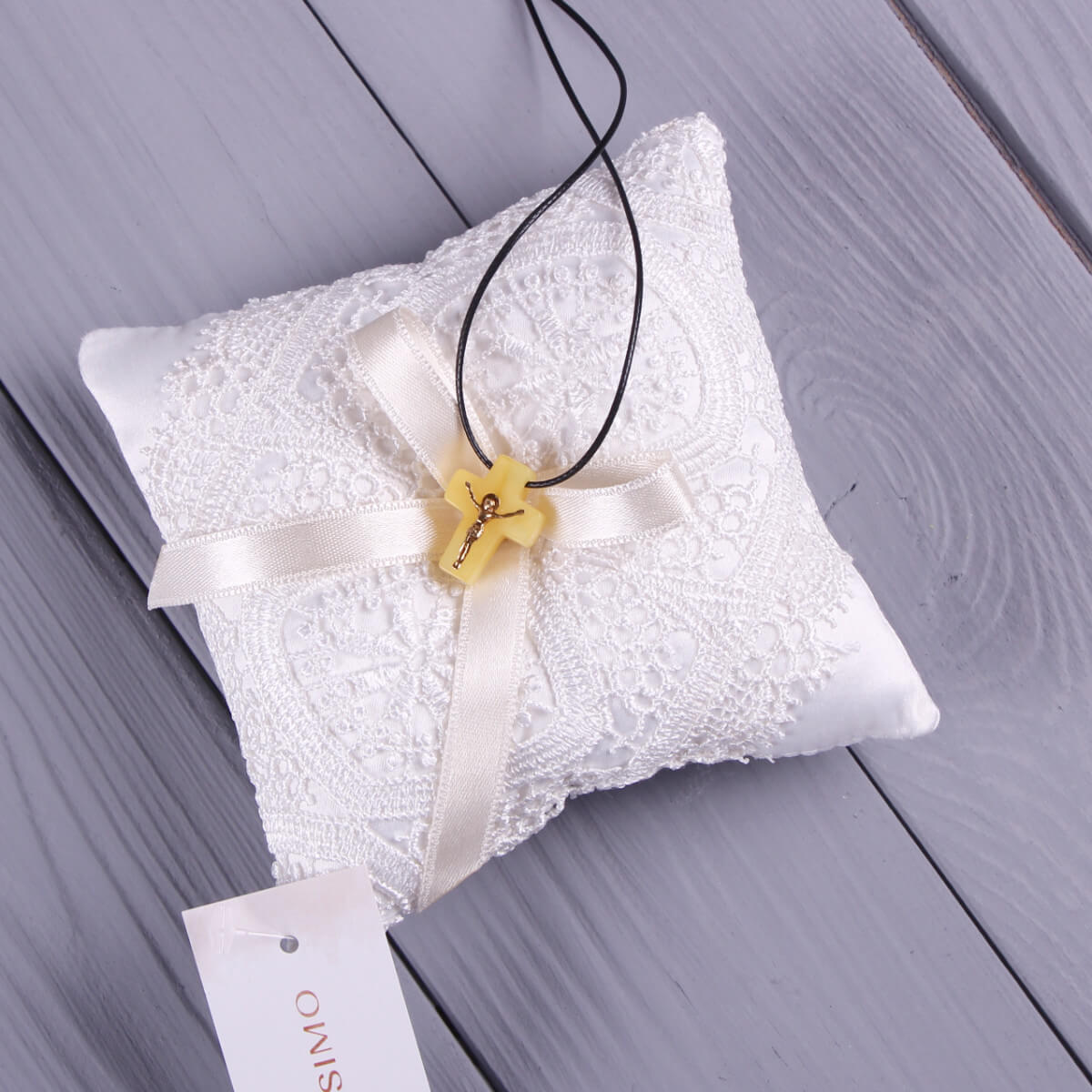 Necklace with a yellow cross on a Baptism Cross Pillow on a wooden surface