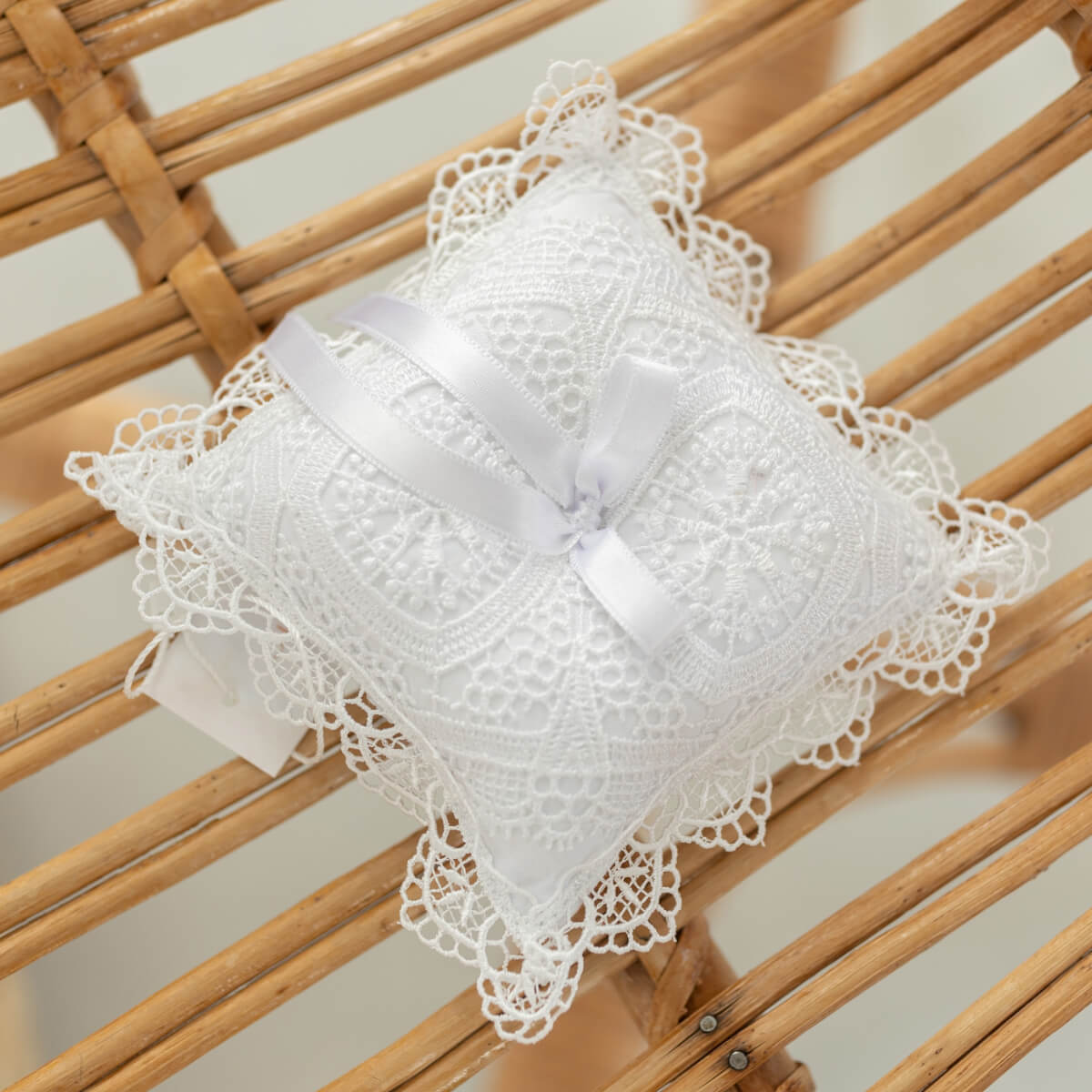 Baptism Cross Pillow with a bow on a wooden surface