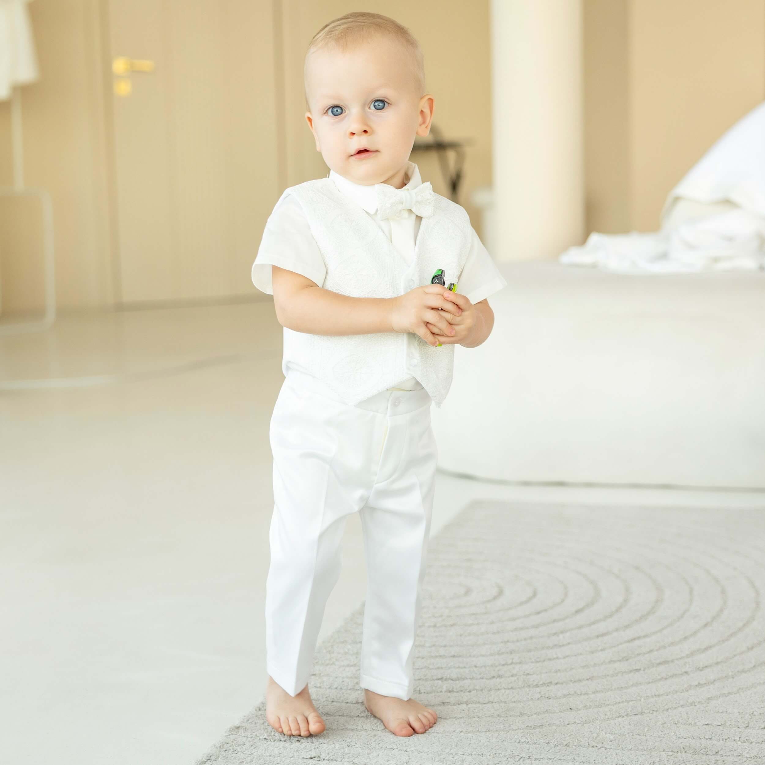 Baby in a Baby Boy Baptism Suit standing on a light-colored carpet