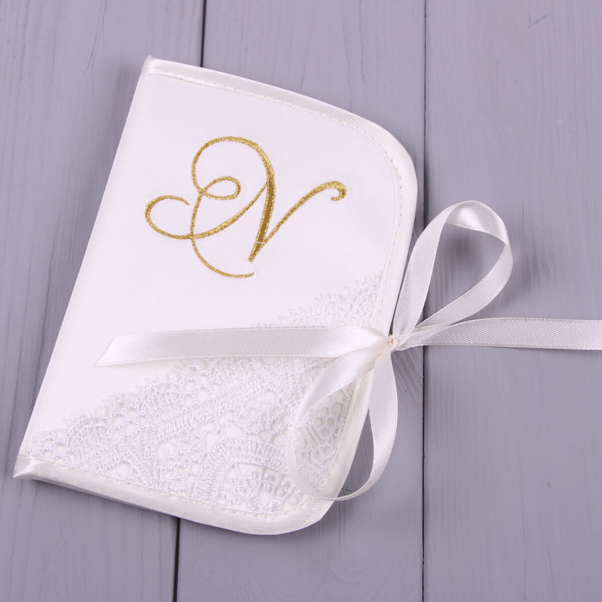 White embroidered tfirst curl box, part of  Boys Christening Outfit  on a gray wooden surface