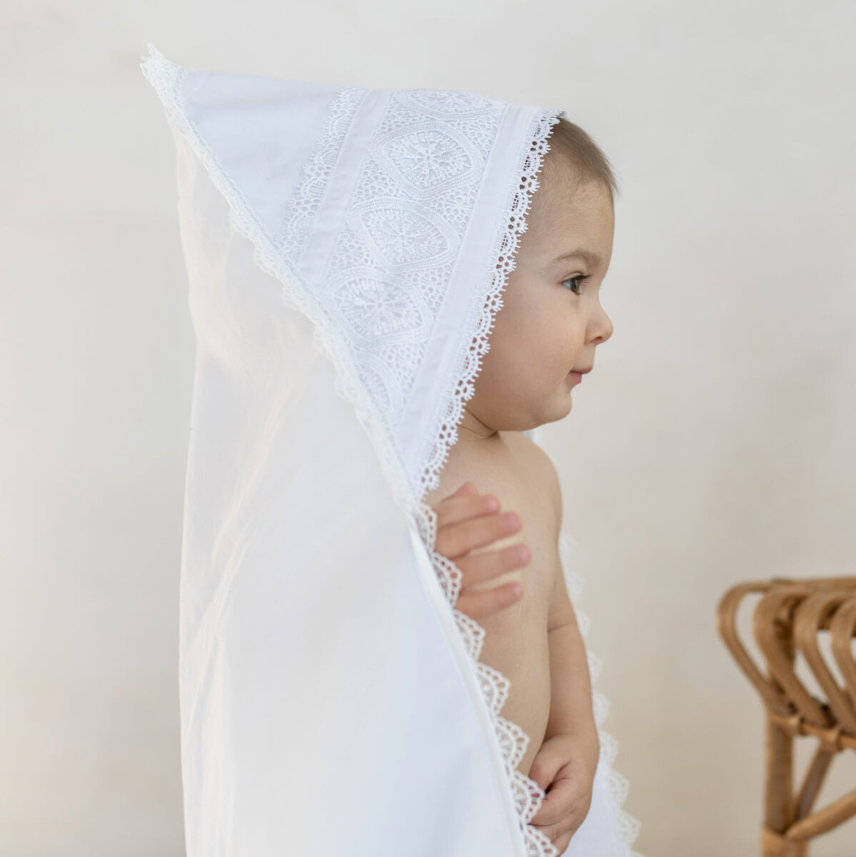 Baby wearing a white lace hooded baptism blanket