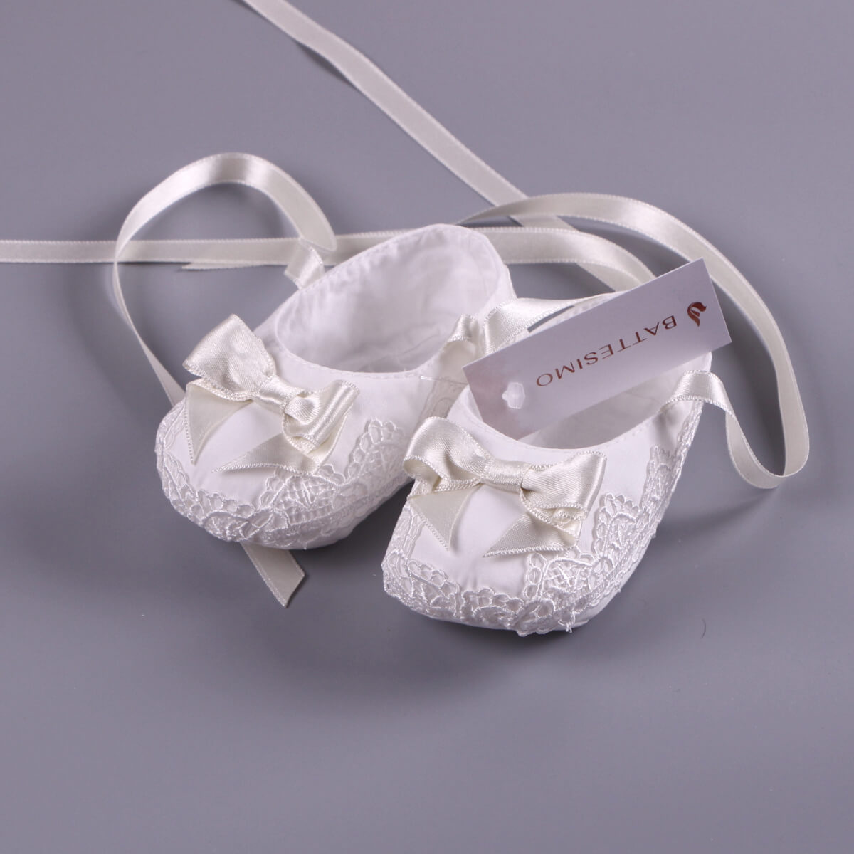 Christening Booties with ribbons on a gray background