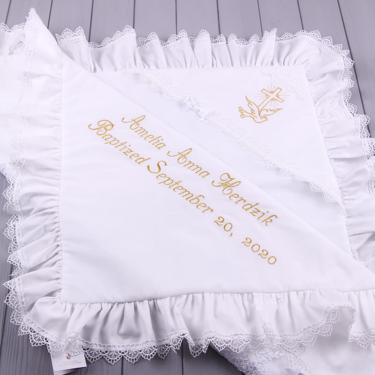 White embroidered baby blanket with yellow text and design on a wooden surface