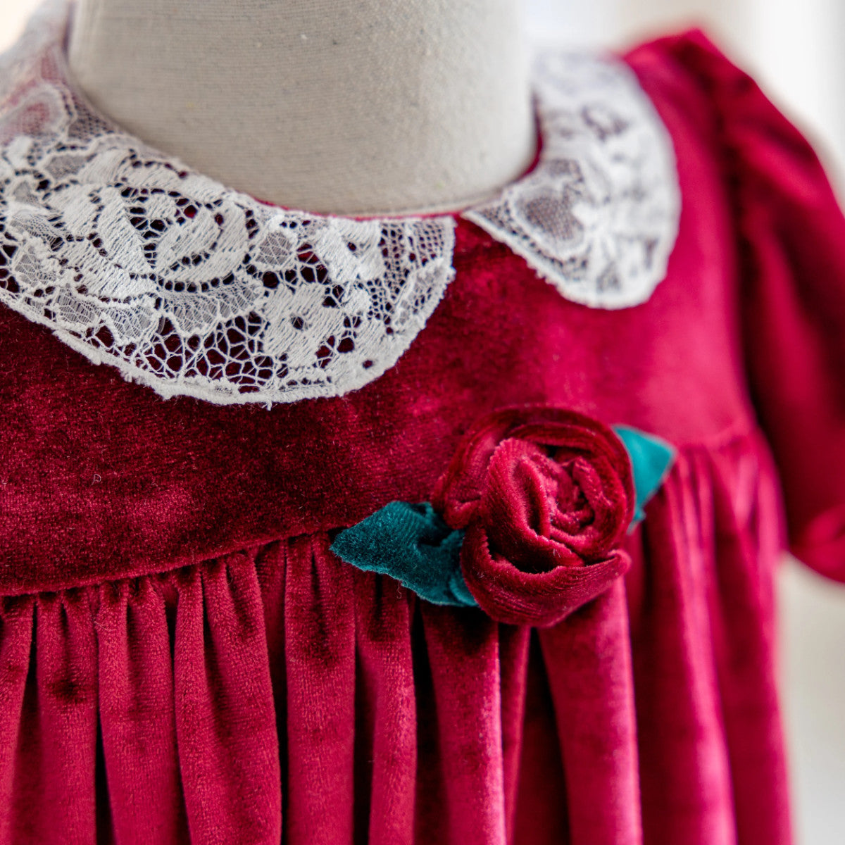Red dress with lace collar and floral detail on a mannequin