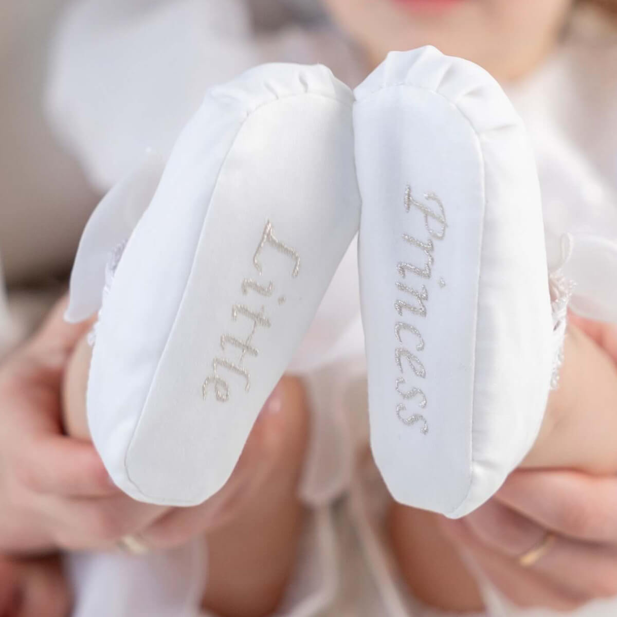 White baby booties with 'Little Princess' text held by a person.
