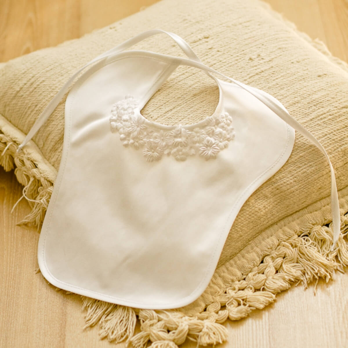 Newborn Bib with lace details on a textured beige surface