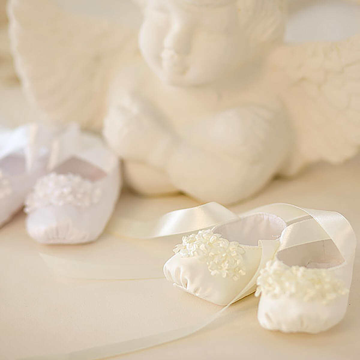 Christening Booties with decorative elements on a soft beige background