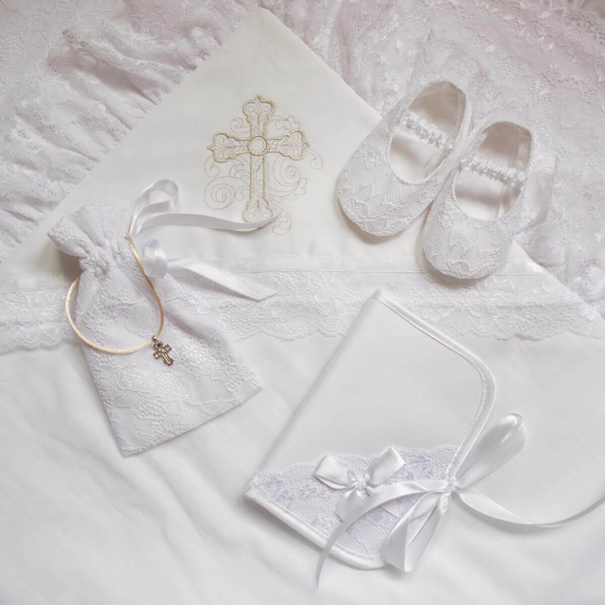 Baptism Keepsake Pouch, bib, and necklace with cross design on a light background