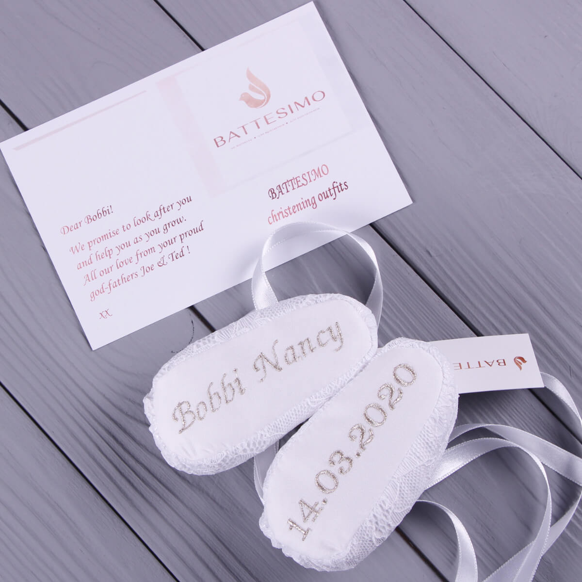  Christening Booties with embroidery and a card on a wooden surface
