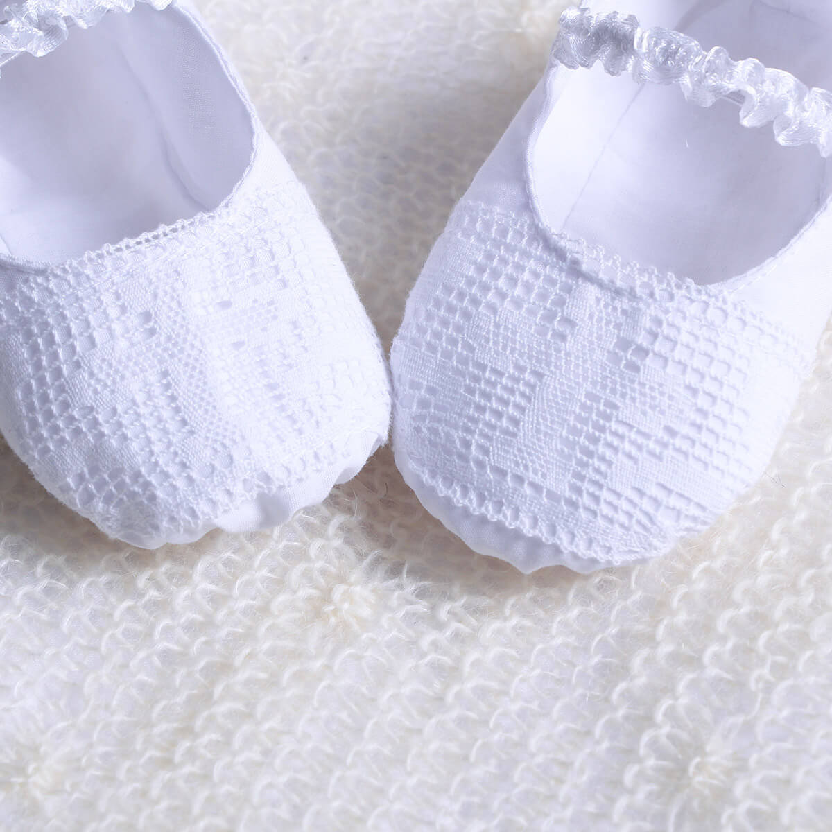  Christening Booties with textured sole on a white textured background