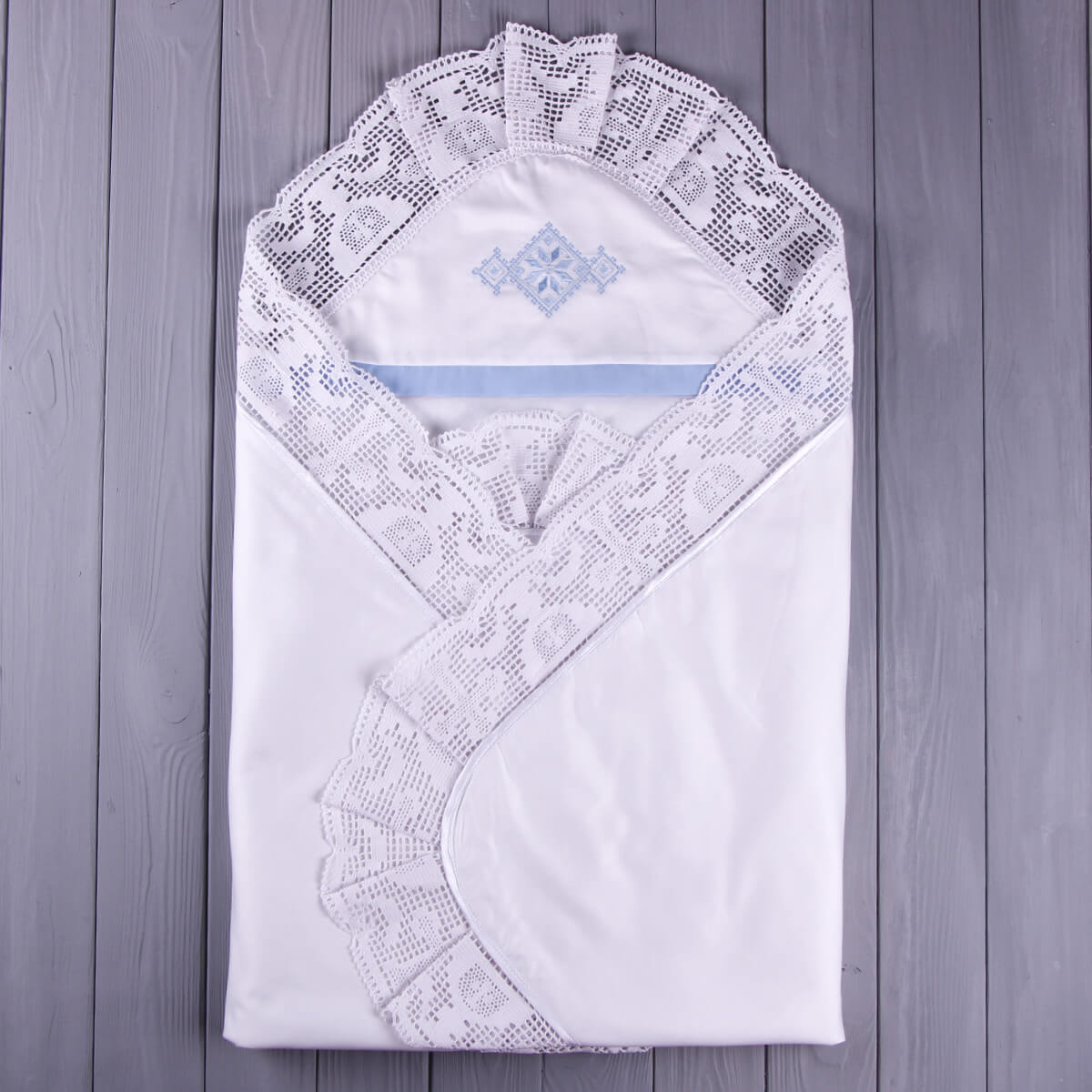 White embroidered baby blanket on a wooden surface