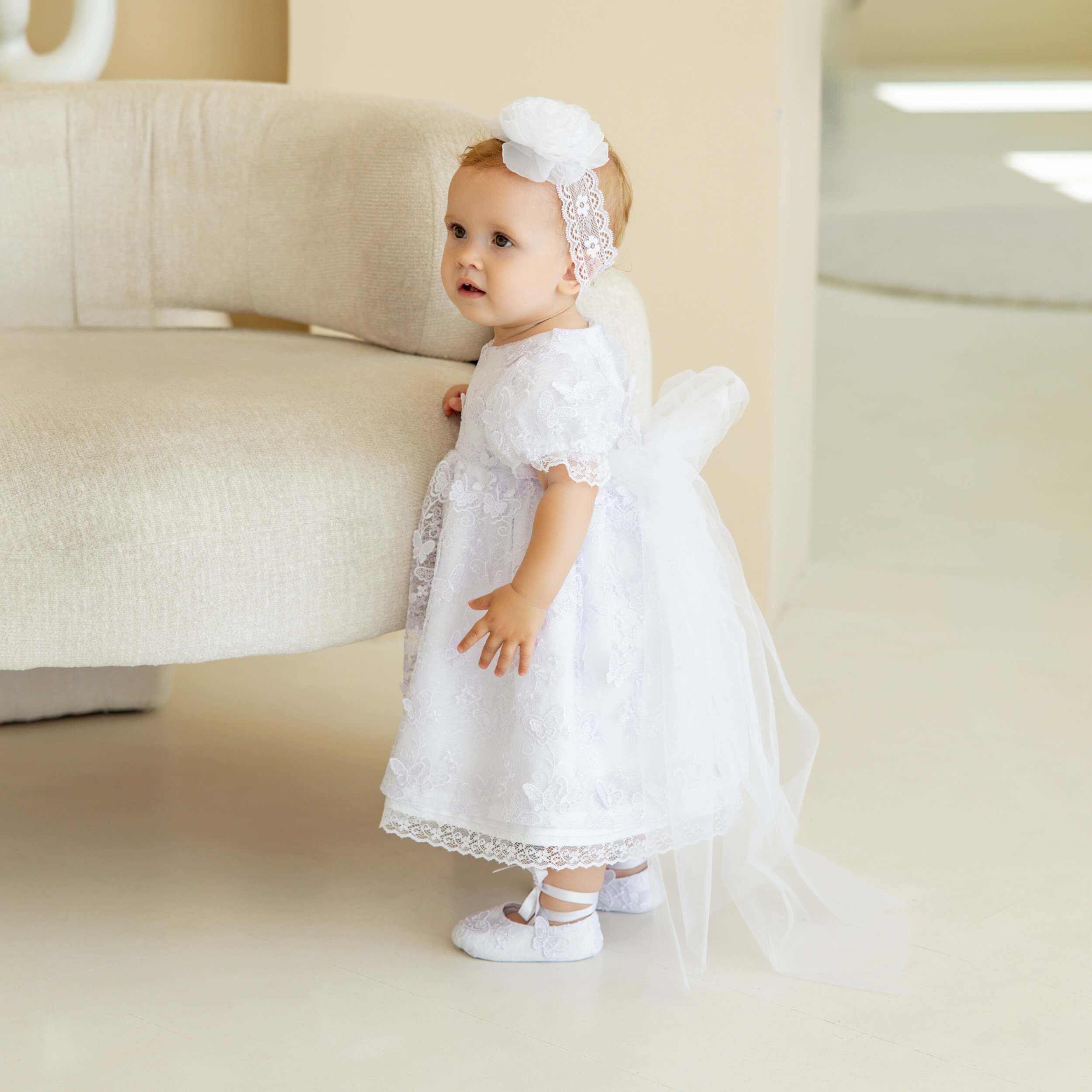 Baby in Baby head band standing in a room.