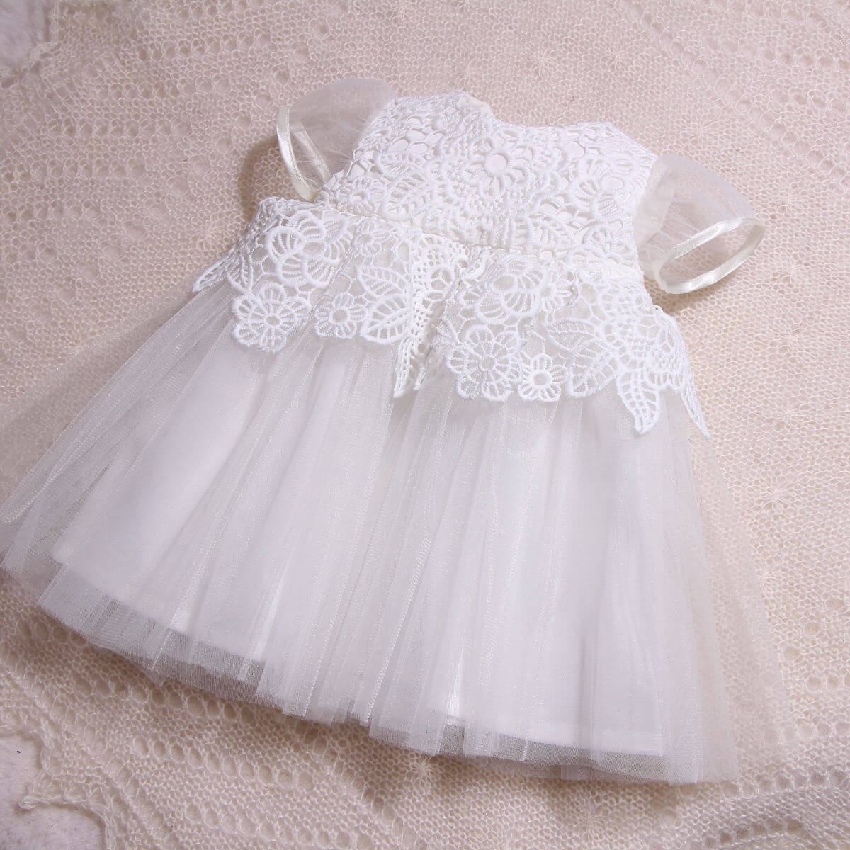 Christening Lace Dress on a textured beige surface