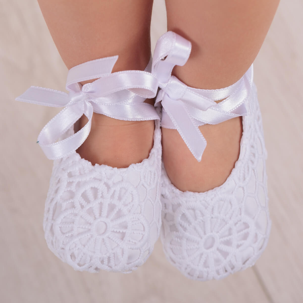 Christening Booties with ribbons on a neutral background