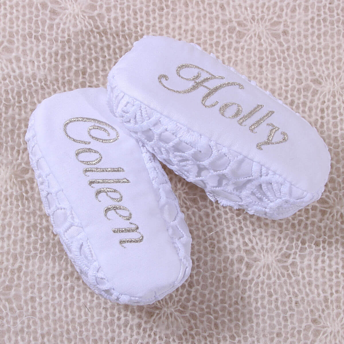 Christening Booties with embroidered names on a textured beige background