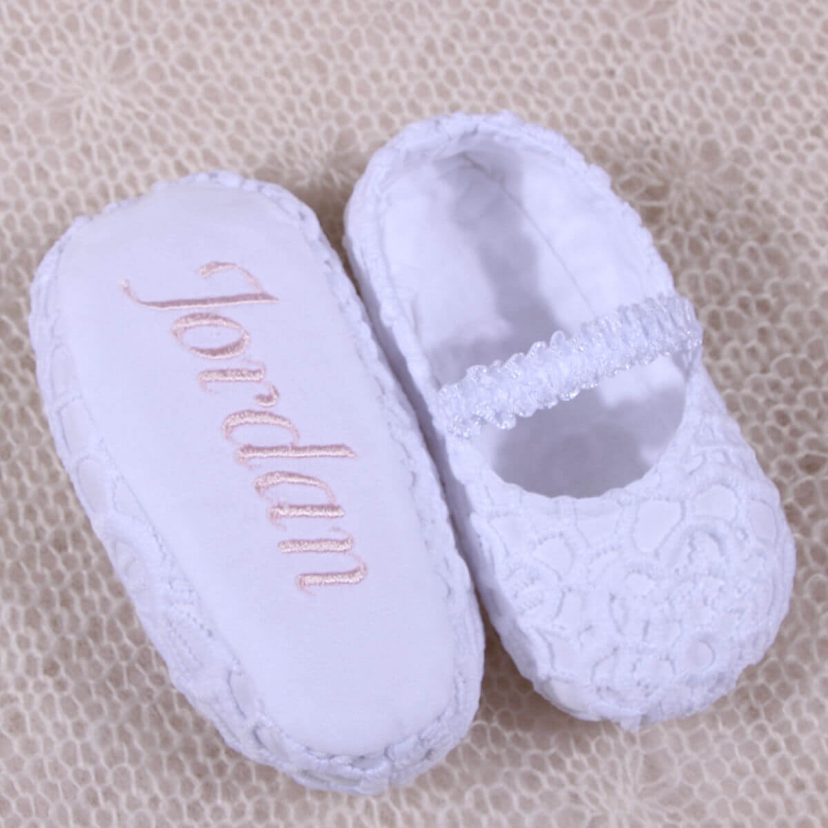 Christening Booties with 'Jordan' embroidered on a beige textured background