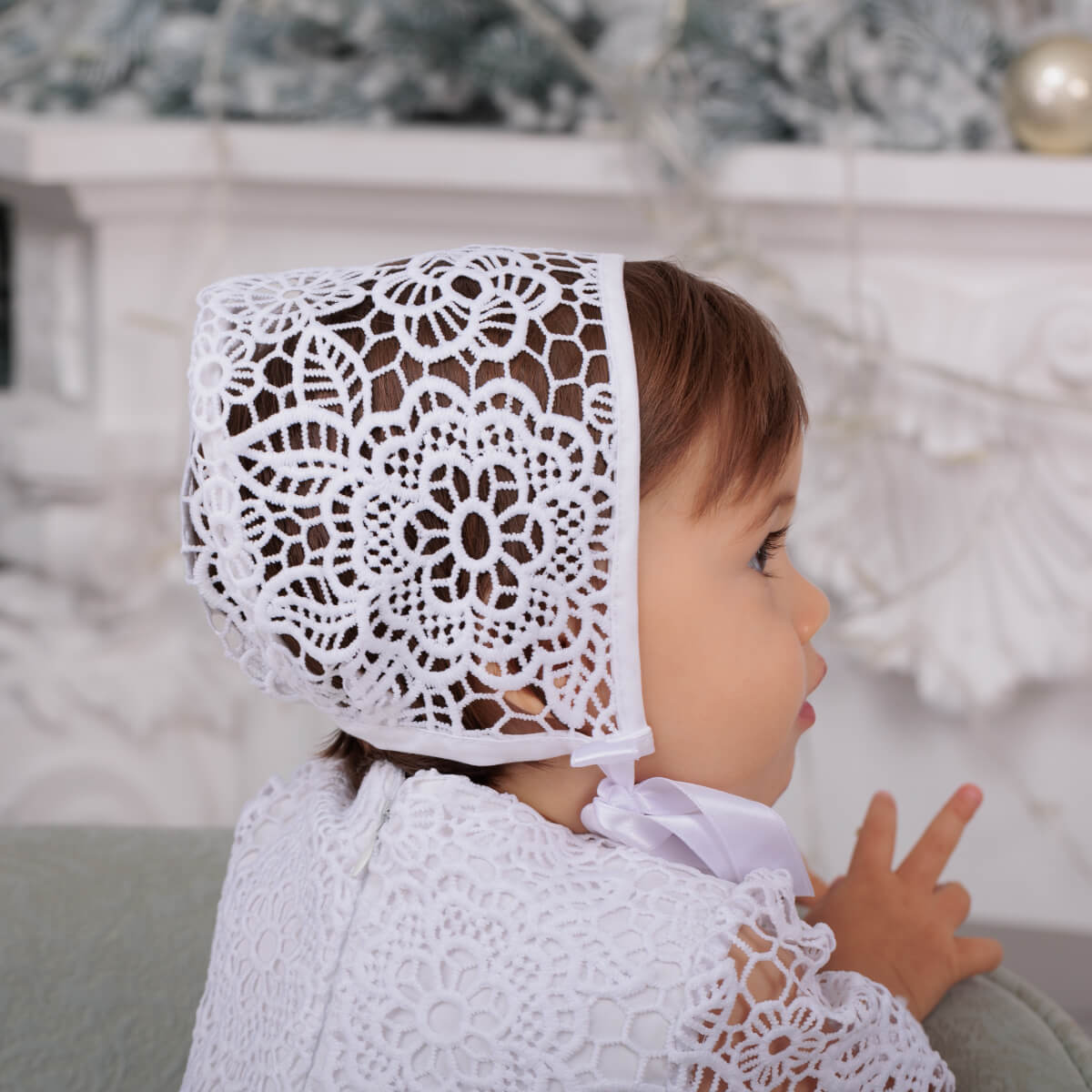 Child wearing a Lace Baptism Bonnet in a festive indoor setting