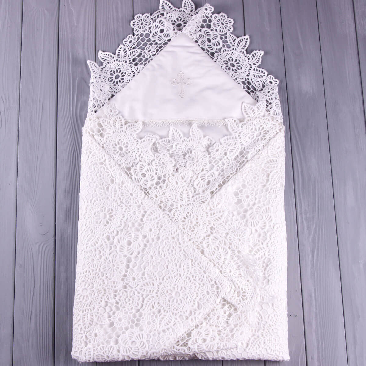 White lace baptism blanket on a wooden surface