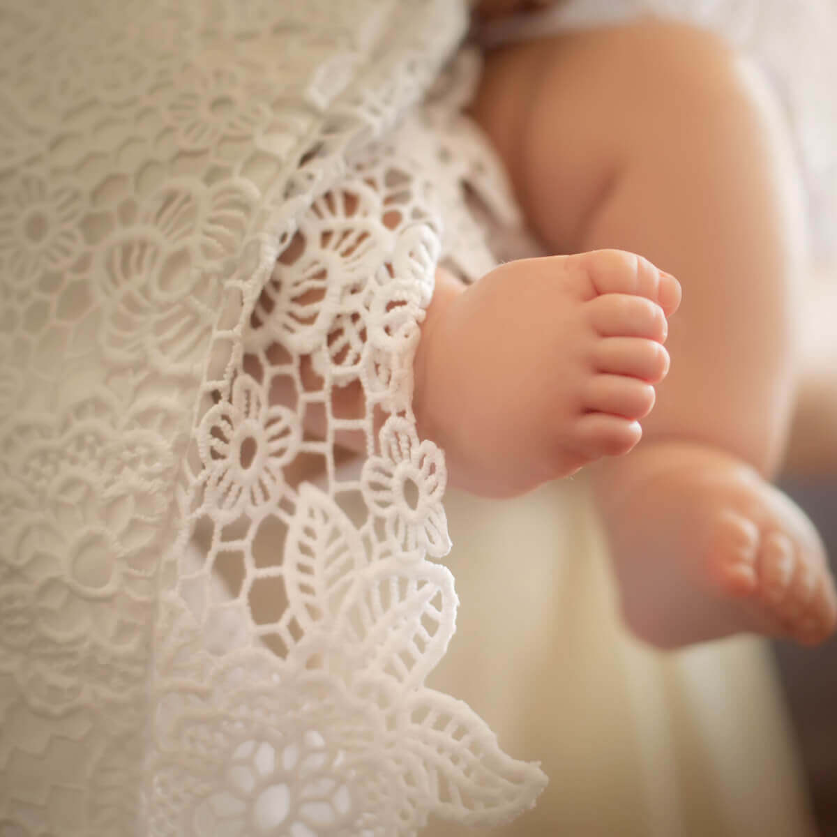 Close-up of a baby's feet in lace baptism blanket in the background