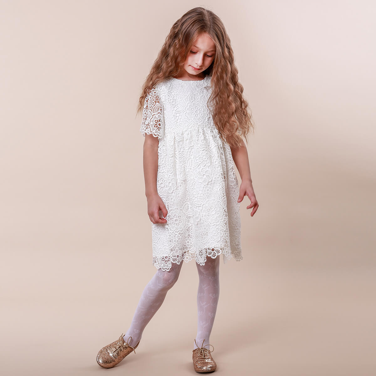 Young girl wearing a white lace dress on a beige background