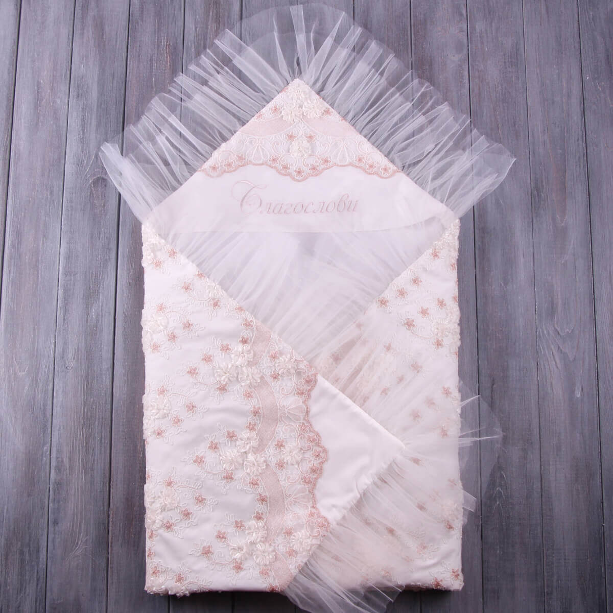 Decorative baptism blanket with lace and tulle on a wooden surface