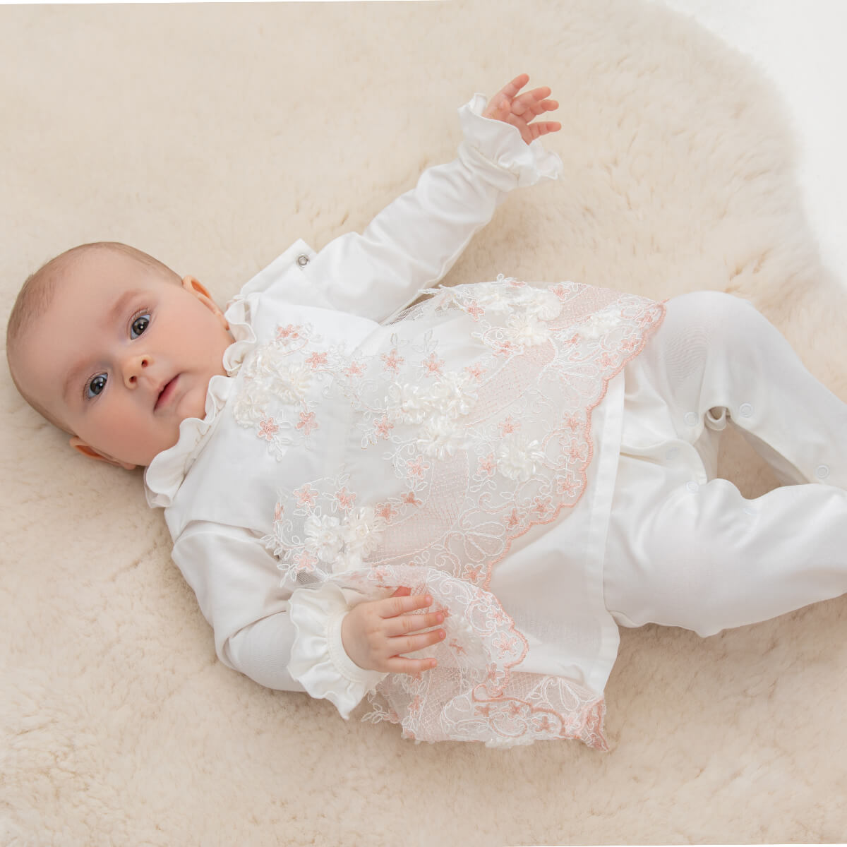 Baby lying on a soft surface wearing a Coming Home Outfit  with floral details
