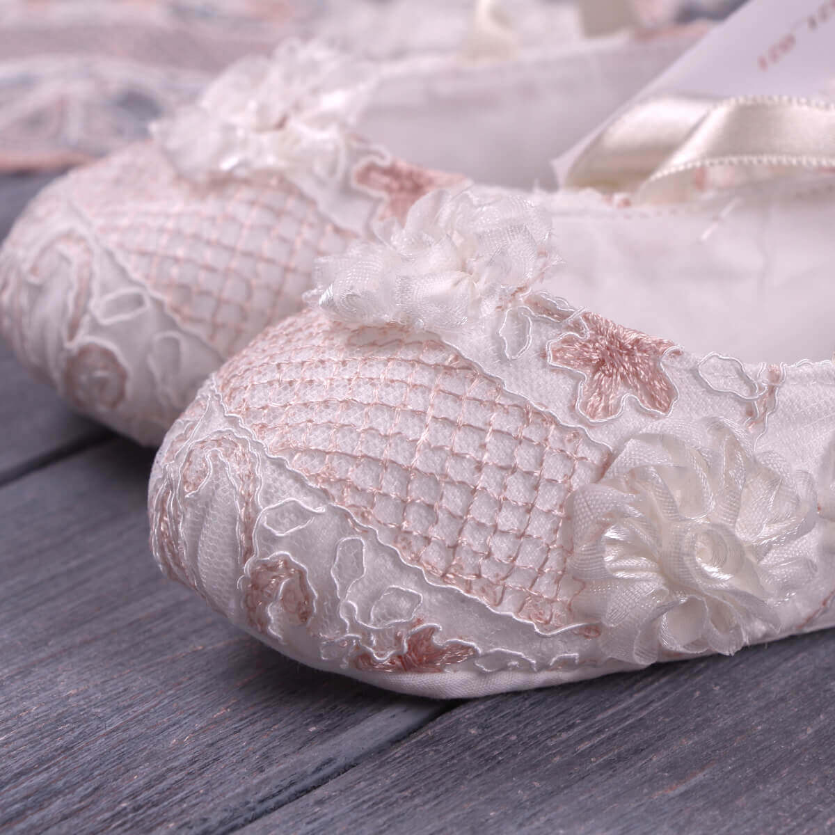 Christening Booties with floral details on a wooden surface